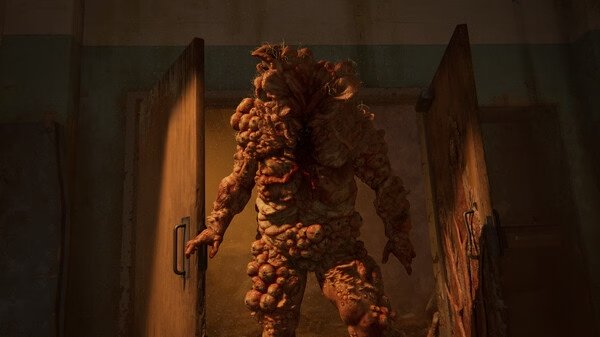 A bloater stands menacingly in an open doorway in a dark room. The Last of Us Part I screenshot.