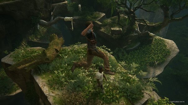 Screenshot from UNCHARTED: Legacy of Thieves Collection showing two characters exploring a lush, overgrown cliffside environment.