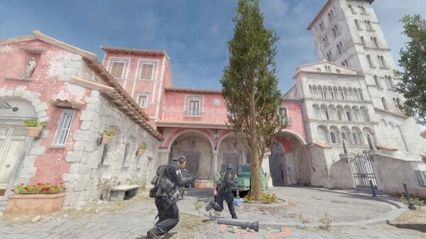 Counter-Strike 2 screenshot: Two armed players navigate a sunny courtyard with a tall tree and historic buildings in view.