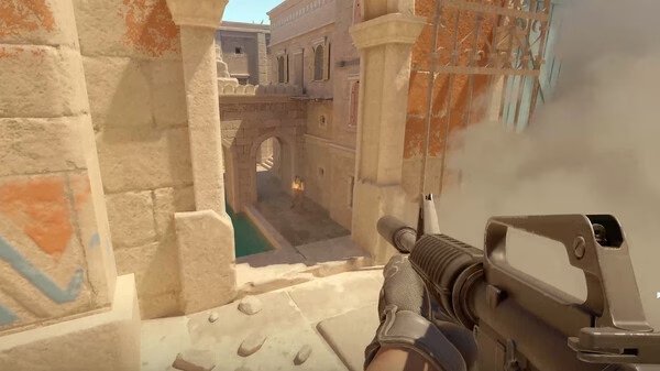 Counter-Strike 2 screenshot: Player holding a rifle aims at an archway in a desert-themed map, with smoke billowing nearby.