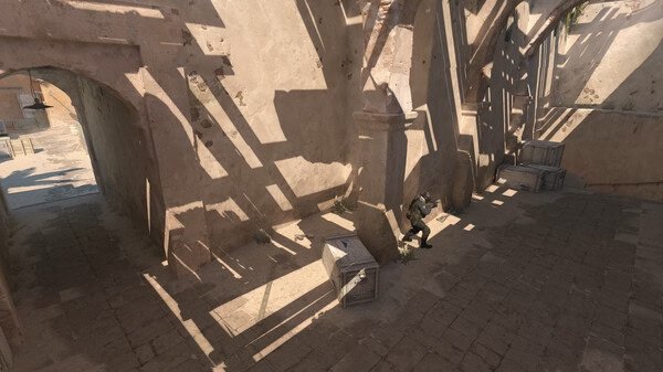 A Counter-Strike 2 screenshot showing a player crouching behind crates in a sunlit alleyway with textured stone walls.