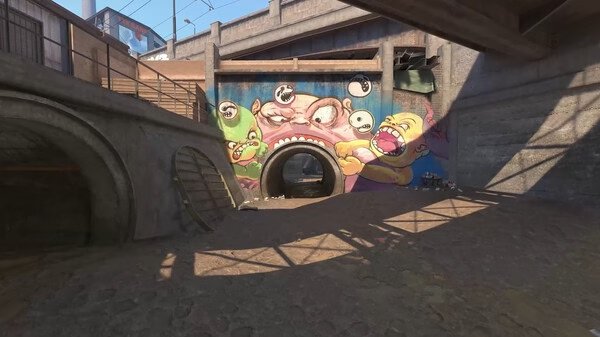 Counter-Strike 2 screenshot showing a tunnel entrance with colorful graffiti featuring cartoon monsters on the wall.