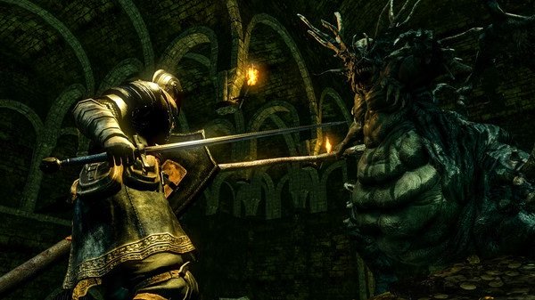 A knight battles a large, grotesque creature in a dimly lit dungeon in this DARK SOULS™: REMASTERED screenshot.