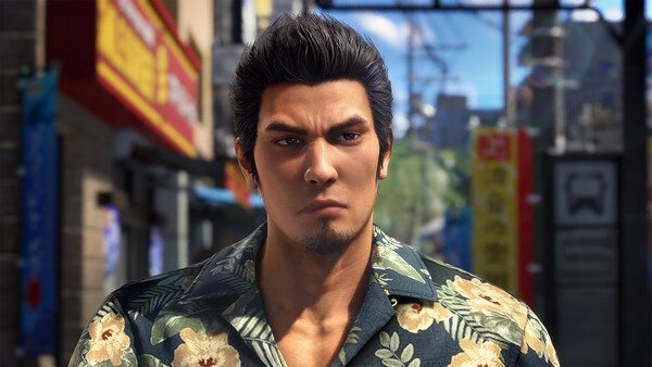 Screenshot from Yakuza Kiwami 3 & Dark Ties showing a character in a floral shirt standing on a lively city street.