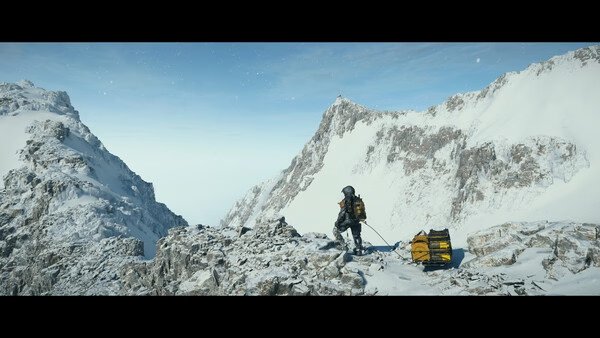 DEATH STRANDING 2: ON THE BEACH screenshot shows a lone figure in winter gear climbing snowy mountains with a gear-laden sled.