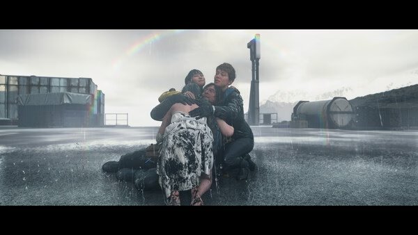 Screenshot from DEATH STRANDING 2: ON THE BEACH showing a group of characters huddled together in the rain on a desolate landscape.