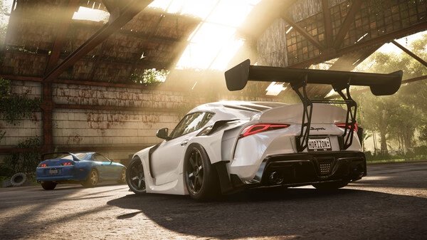A Forza Horizon 5 screenshot showing a white Toyota Supra with a large rear wing, parked in a sunlit, abandoned warehouse setting.