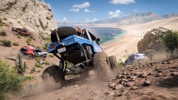 Forza Horizon 5 screenshot: Off-road race with trucks on a rocky desert path, ocean and mountains visible in the background.