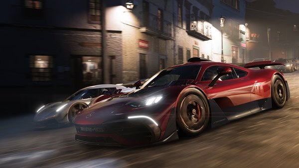 Forza Horizon 5 screenshot: Two high-speed sports cars race through a dimly lit street, showcasing realistic graphics and dynamic lighting.