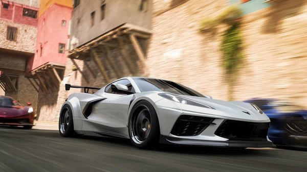 A Forza Horizon 5 screenshot featuring a white sports car speeding through a colorful town, with other cars in the background.