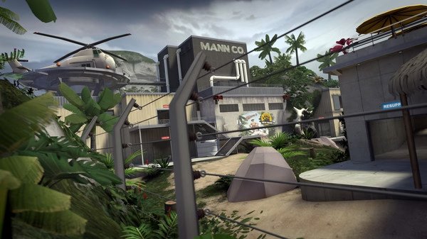 Screenshot of Team Fortress 2 showing a tropical map with a Mann Co. building, helicopter, and lush vegetation in the foreground.