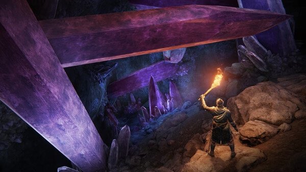 A screenshot from Elden Ring showing a player holding a torch, exploring a cave filled with massive glowing purple crystals.