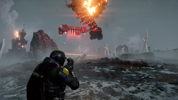HELLDIVERS 2 screenshot: A soldier aims at a burning spaceship crashing in a rocky, alien landscape under a cloudy sky.