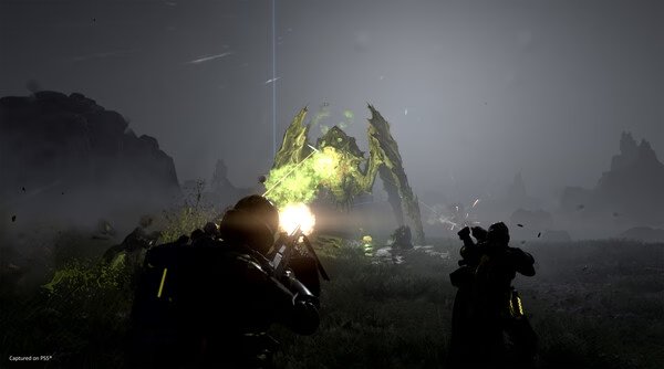 HELLDIVERS 2 screenshot: Players engage a glowing alien creature in a foggy battlefield, firing weapons amidst intense combat action.