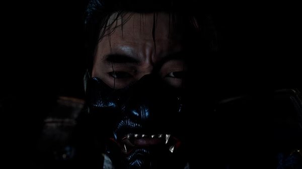 A screenshot from Ghost of Tsushima DIRECTOR'S CUT showing a samurai in dark armor standing against a shadowy background.