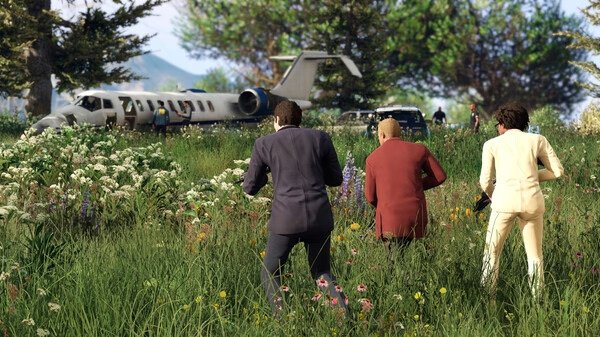 Grand Theft Auto V screenshot showing three characters in suits approaching a jet in a flower-filled meadow.