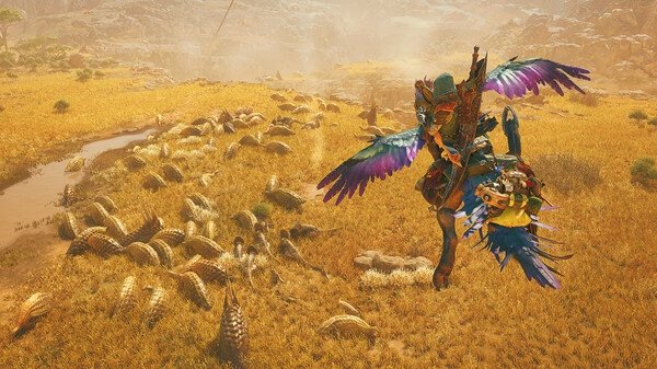Screenshot from Monster Hunter Wilds showing a hunter with colorful armor and wings leaping over a field of grazing creatures.