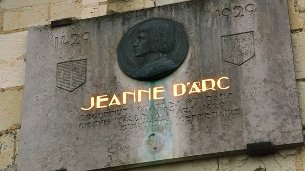 Plaque of Jeanne d'Arc in Age of Empires IV screenshot, featuring engraved text and dates on a stone wall.