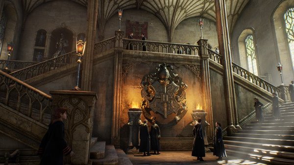 Screenshot from Hogwarts Legacy showing students and faculty gathering in the grand, ornate entrance hall with a large crest.