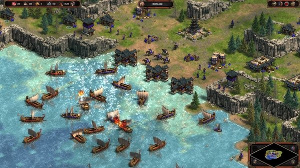 Screenshot from Age of Empires Definitive Edition shows a naval battle with multiple ships near a coastal settlement.