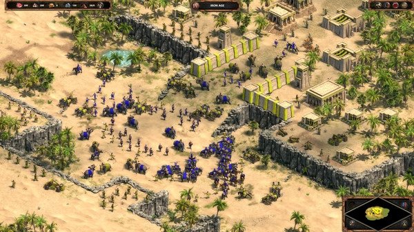 Screenshot of Age of Empires Definitive Edition showing a large battle with armies and elephants in a desert settlement.