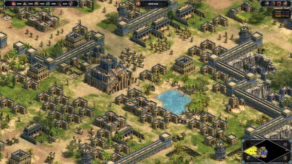 Age of Empires Definitive Edition screenshot showing a sprawling ancient city with a central temple, soldiers, and a small lake.