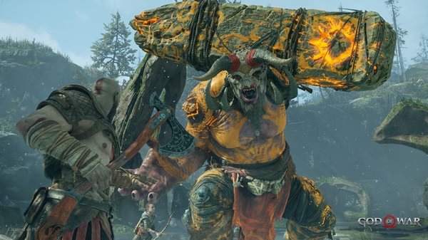 Kratos battles a towering troll holding a flaming stone pillar in a lush forest in this God of War screenshot.