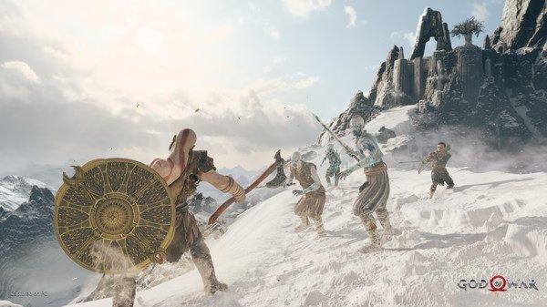 God of War screenshot: Kratos battles several enemies with a shield and axe on a snowy mountain landscape under a clear sky.