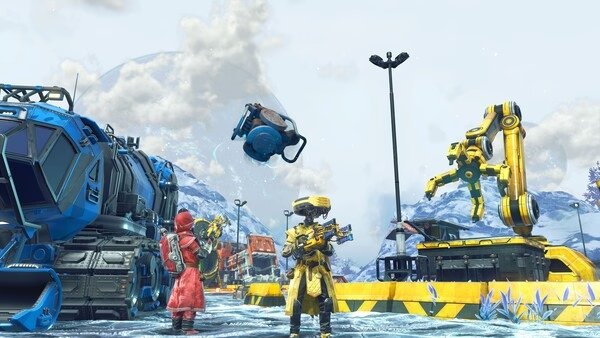 No Man's Sky screenshot: Two characters stand on icy terrain, surrounded by machinery and a flying drone under a cloudy sky.