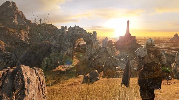 Dark Souls II: Scholar of the First Sin screenshot featuring a knight approaching ruins under a golden sunset near the ocean.