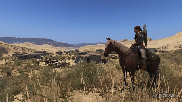 Screenshot from Mount & Blade II: Bannerlord showing a mounted warrior overlooking a desert village with mountains in the background.