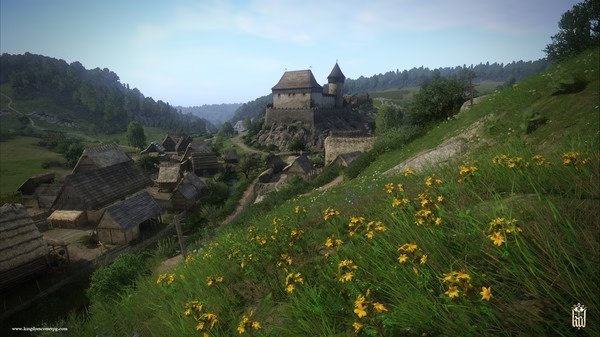 Screenshot from Kingdom Come: Deliverance showing a medieval village with a castle on a hill and wildflowers in the foreground.