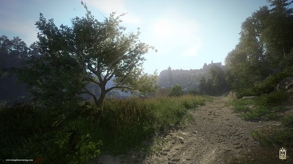 Screenshot from Kingdom Come: Deliverance showing a scenic dirt path with a tree on the left and a distant castle under a clear sky.